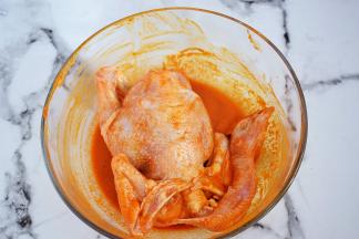 再把三黄鸡放入全身涂抹上腌料