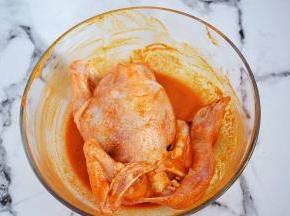 再把三黄鸡放入全身涂抹上腌料