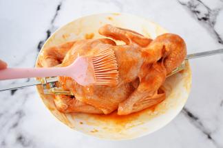 把煮沸的蜜汁腌料先在三黄鸡全身涂抹一遍，不要全涂完，留下一点，因等下还要再刷一遍，这样能让鸡烤出来颜色更漂亮