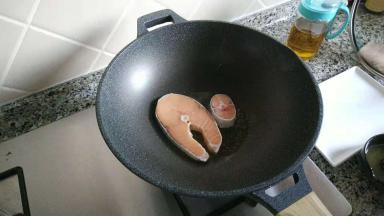 锅子烧热，倒入食用油，放入三文鱼，盖上锅盖