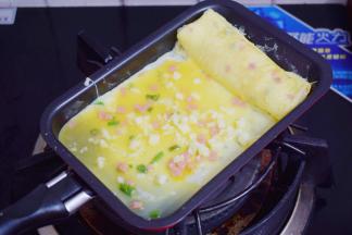 再舀进1大勺鸡蛋液，再撒上芝士碎，小火煎至底部凝固