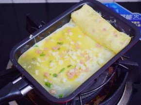 再舀进1大勺鸡蛋液，再撒上芝士碎，小火煎至底部凝固