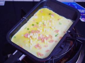 迷你煎锅小火烧热，舀进1大勺鸡蛋液，再撒上芝士碎，小火煎至底部凝固