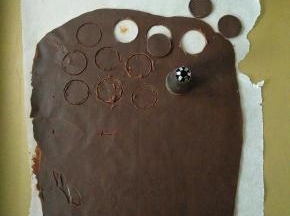 用少量巧克力在油纸上挤上眼睛和鼻子，剩余巧克力倒在铺好油纸的烤盘上，表面再铺张油纸擀平待凝固，用热的裱花嘴刻出小熊耳朵。