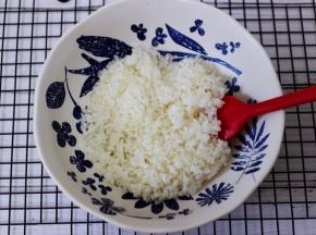 把蒸熟的米饭放入一个大一点的碗里面。