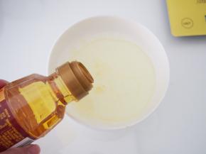 将牛奶、玉米油倒在碗中混合均匀。