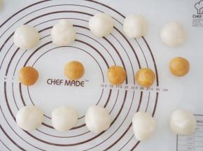 将冰皮面团分成30g左右一个，揉成团；将奶黄馅分成20g左右一个，揉成团。