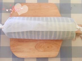 用擀面杖卷住油纸，顺势往上推，卷起来，两边跟拧糖一样拧起来。放入冰箱冷藏半小时后再切块食用。