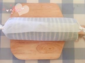 用擀面杖卷住油纸，顺势往上推，卷起来，两边跟拧糖一样拧起来。放入冰箱冷藏半小时后再切块食用。