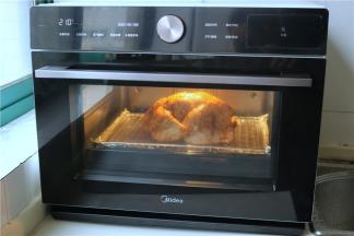 美的蒸烤箱选择菜单中的烤鸡程序，把鸡放入，按开始键，接下来就剩下等待了。