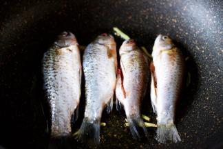 把沥干水分的鲫鱼放入锅中小火慢慢煎至。