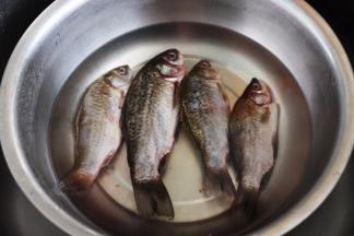 首先把鲫鱼的内脏取出，洗净后的鲫鱼放入加入适量清水的盆中，倒入料酒来继续泡出血水。