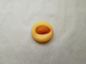 取一个搓好的小圆球压扁，再取一粒大杏仁，在装蛋液的小碗里沾上一点蛋液，放在压扁的面团中间，稍微用力压一下，一个杏仁饼干就做好了。