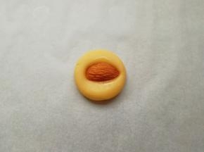 取一个搓好的小圆球压扁，再取一粒大杏仁，在装蛋液的小碗里沾上一点蛋液，放在压扁的面团中间，稍微用力压一下，一个杏仁饼干就做好了。