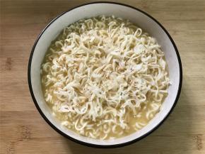 然后把打散的鸡蛋液倒入沥干水分的泡面中，再把虾皮放在上面。