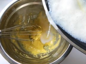 将热牛奶一点点加入到蛋黄糊中，边加入边快速搅拌，将液体搅拌均匀，无颗粒
