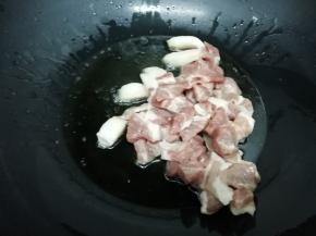 锅中加入适量的油烧到七成热时，把梅头肉放入锅中，煸炒到变色