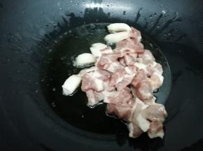 锅中加入适量的油烧到七成热时，把梅头肉放入锅中，煸炒到变色