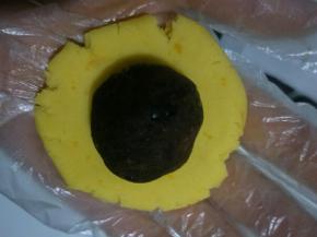 取一个面团按成中间厚周边薄的面皮，包入豆沙馅