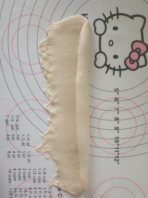 取一个面团擀开成椭圆形，从上卷起。收紧封口。