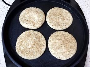 电饼铛上下盘预热，刷一层食用油，放上做好的烧饼胚，选择电饼铛的“烙饼”功能启动。