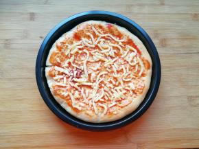 烤制好的饼皮从烤箱里取出，抹上一层番茄酱，撒上一些马苏里拉芝士。