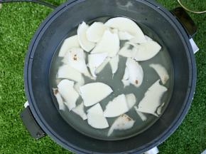 椰青钻孔，倒出椰汁，同时把椰肉挖出来，放入九阳玉京火锅中，再加入适量清水。