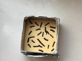 将芝士糊倒入到模具中。饼底部分剩下的材料，再次擀成薄片，切成小条。撒在蛋糕表面装。