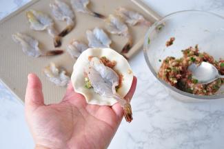 取一个饺子皮，放在适量肉馅，然后放入一个虾。