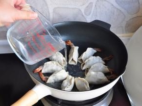 开火，将饺子的底壳煎至上色，微微黄的状态，加入水，没到饼子二分之一处即可。盖上锅盖大火烧开后转中火。