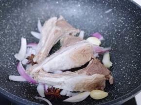 起油锅，加入洋葱香料炒出香味儿。再加入焯水的羊排，翻炒至水分干。