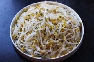 把焯过水的绿豆芽捞出沥干水分后、放入一个深一点的盘子里。