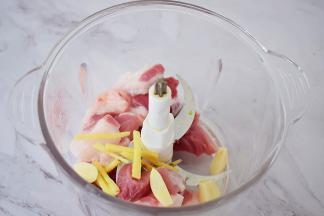 把猪肉放入料理机中，加入姜丝、蒜片，打成肉末