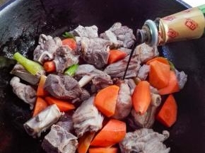 放入一汤匙料酒，放入适量的生抽、老抽，翻炒至羊肉上色
