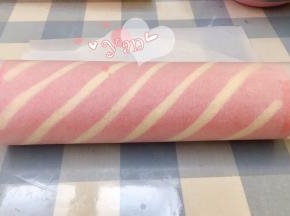 用擀面杖卷住油纸，顺势往上推。卷起来，两边跟拧糖一样拧起来。放入冰箱冷藏半小时后再切块食用。