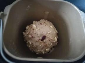 黄油被面团完全吸收以后，检测可以拉出大片比较薄的膜。果干放入面包桶搅拌两三分钟，或者用手压入面团内。