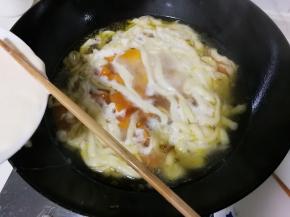 筷子压着碗边的面团，压出比筷子细一点面条，将面条拨下锅，烧开转小火烧一分钟