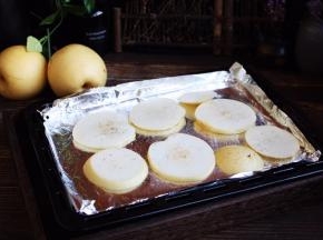 将梨片平铺在烤盘上。