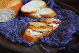 将烤好的蜂蜜梨片对折，放在法棍面包片的柠香酸奶上。