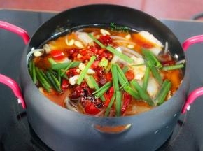把煸炒好剩余的三分之一的辣椒、以及辣椒油、香葱等倒入煮好的鱼盆里。