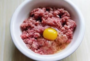 肉糜加入大口器具中，加入一只鸡蛋。