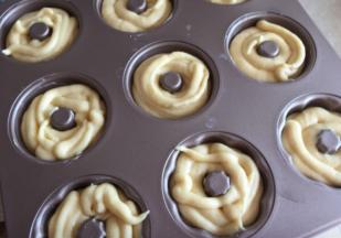 甜甜圈模具抹一层黄油，把面糊挤进模具中，八分满即可