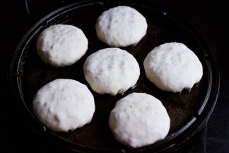 电饼裆提前预热后，把包好的包子放入电饼裆里，用手摁扁包子。