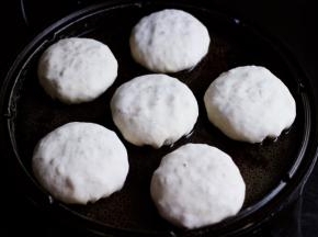 电饼裆提前预热后，把包好的包子放入电饼裆里，用手摁扁包子。