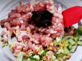 猪肉用刀切成小丁放入盆中，葱姜切碎后放入盆中后加入豆瓣酱。