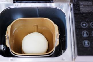 和好的面团用手揉圆后，放入面包机里进行醒发。