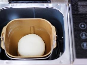 和好的面团用手揉圆后，放入面包机里进行醒发。