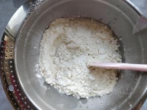 将干酵母倒入水中，再将水倒入上一步的粉质混合物中，加入切成小块的黄油，拌匀。