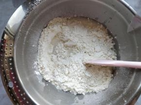 将干酵母倒入水中，再将水倒入上一步的粉质混合物中，加入切成小块的黄油，拌匀。