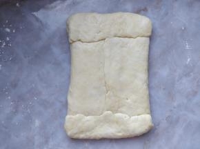 将醒发好的水面团用手稍微按压平整，把油面团包在其中。